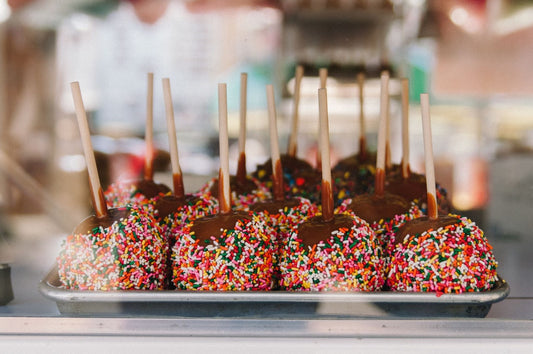 Delicious looking caramel apple pops covered in rainbow sprinkles.