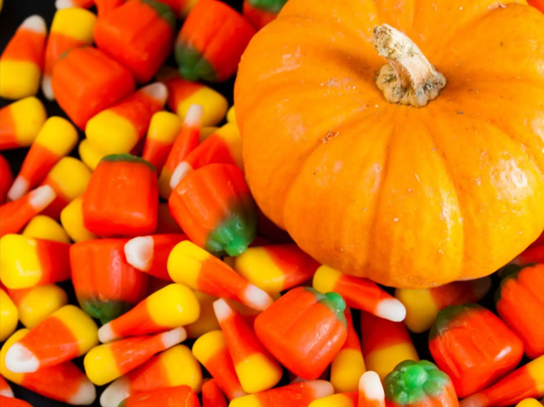 Candy corns surrounding a pumpkin.