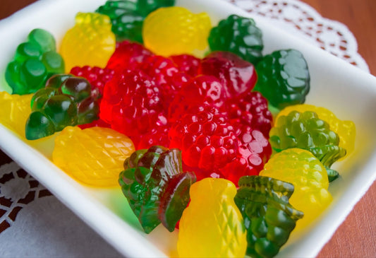 Colorful gummy candies in a white dish set on top of the lacey doily.
