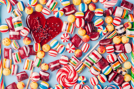 A high angle shot of colorful candies and a heart-shaped lollipop