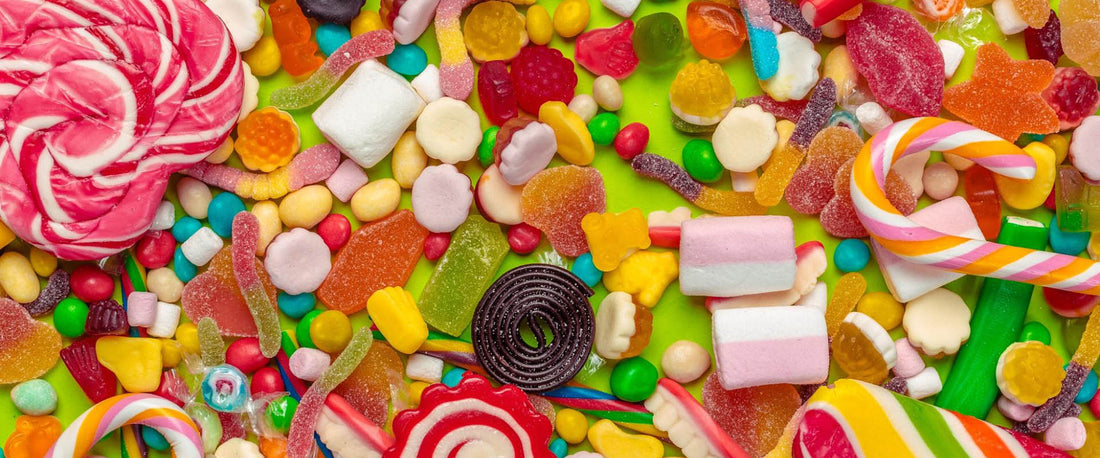 A large assortment of mixed candies on top of a bright green background.