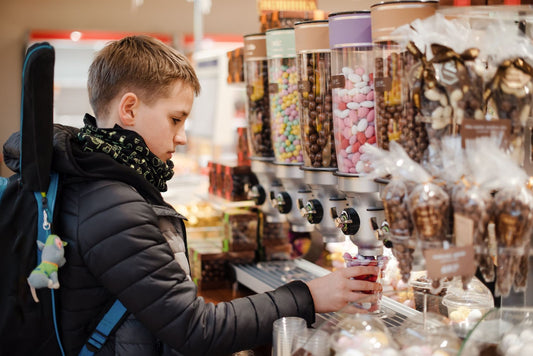 Pre-teen boy fills his cup with candies at a candy store.