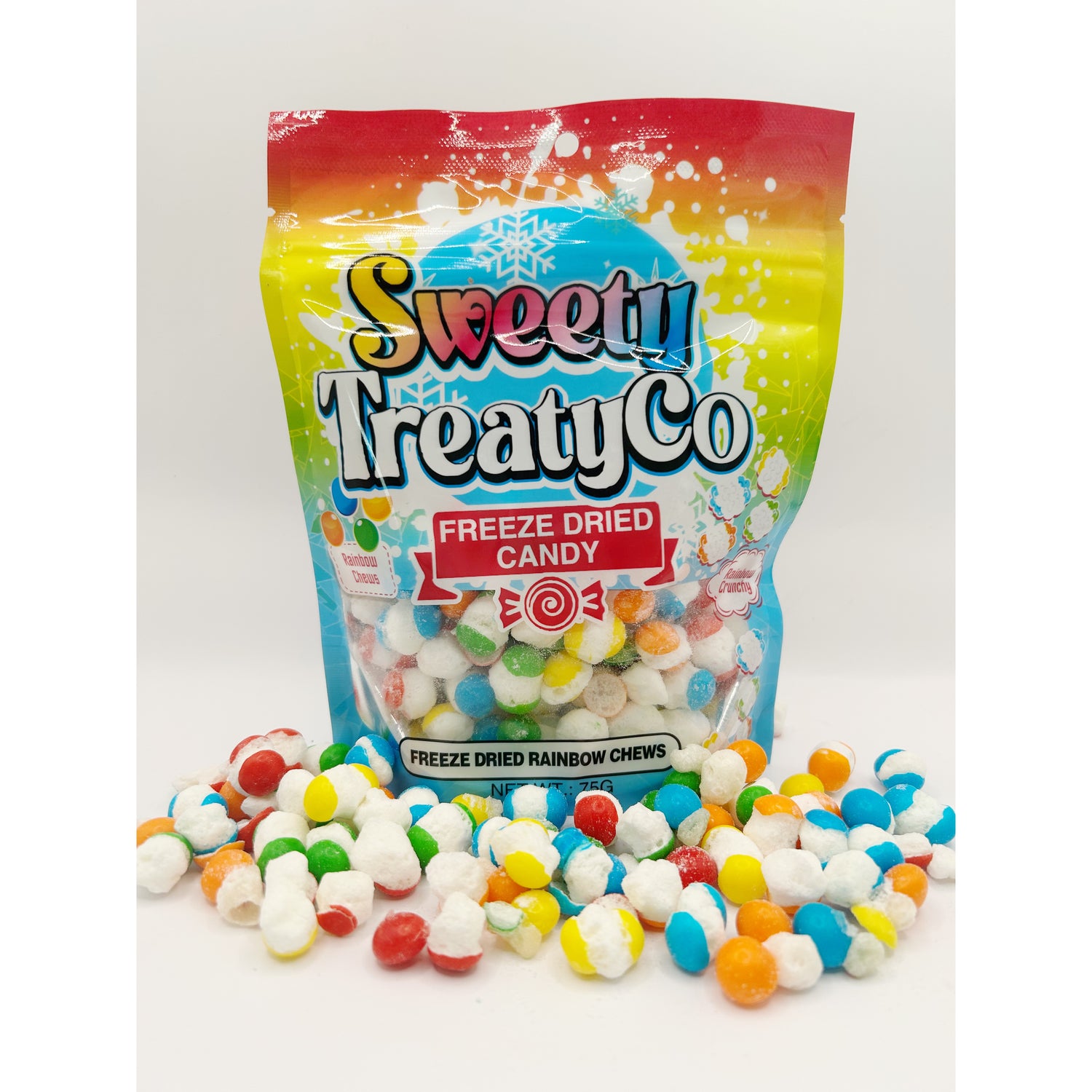 A colorful package of SweetyTreatyCo Freeze Dried Candy with snowflake designs, surrounded by multicolored freeze-dried candies scattered in the foreground on a white surface.